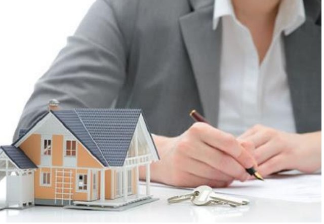 Persona firmando un contrato de arrendamiento junto a una maqueta de casa